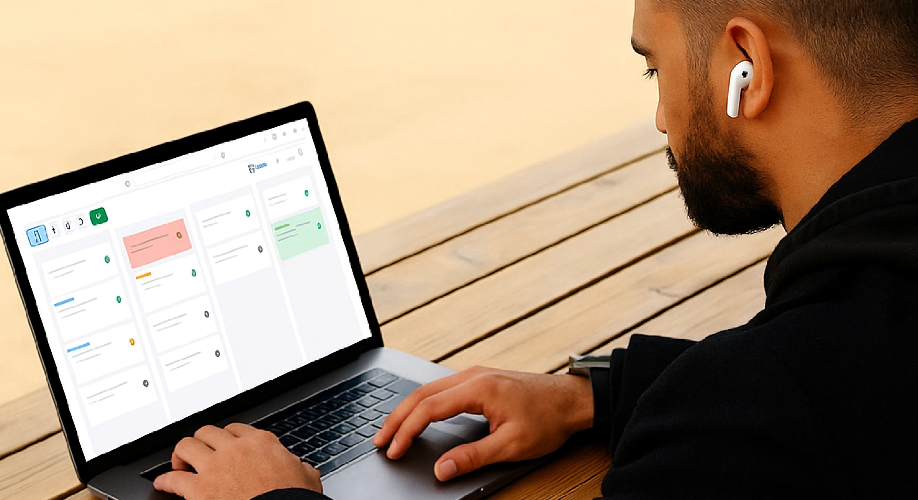 Person using a laptop with a CRM, seated at a wooden table outdoors, wearing wireless earbuds.